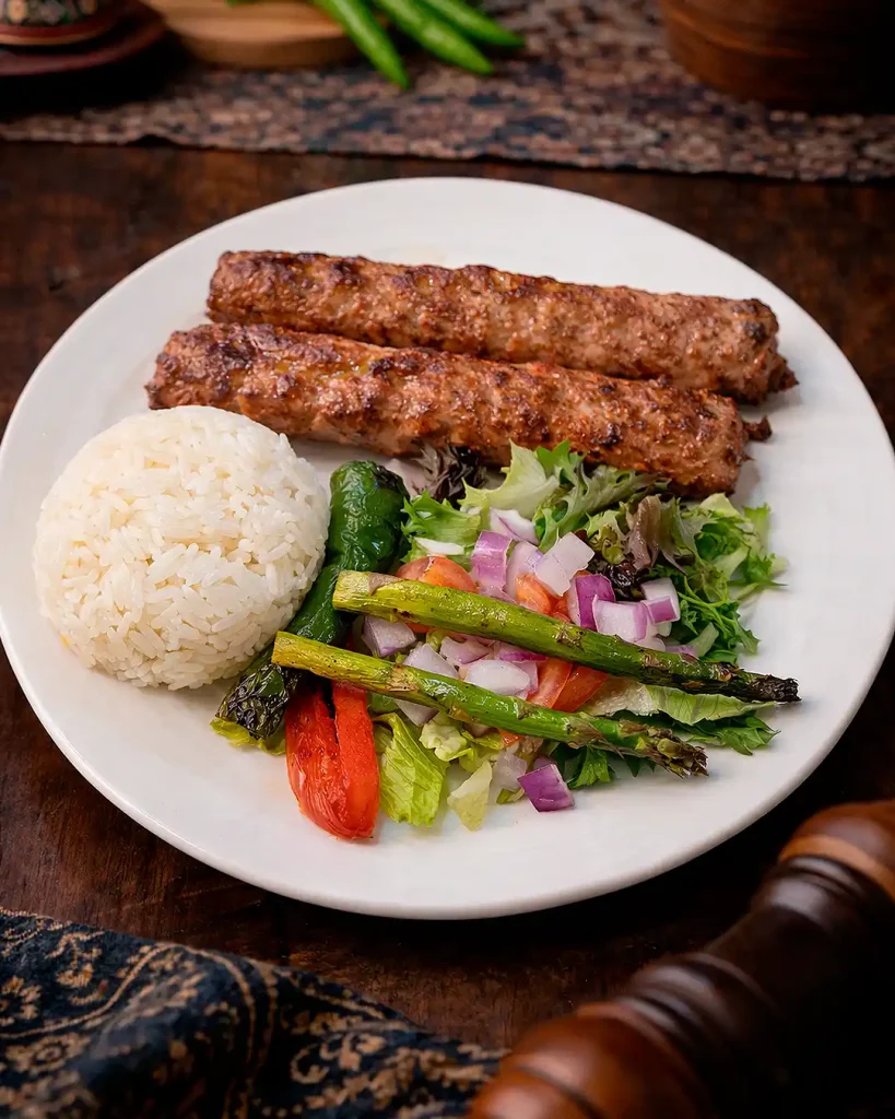 Chicken Adana Ground chicken kebab grilled on skewers, served with rice and salad.